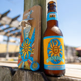 steel bottle opener mounted to wooden plaque featuring Oberon Sun Burst design against wood grain background. Featuring Oberon in white text above opener, with an Oberon sun logo replacing the "O" in the word Oberon