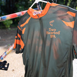 Front view of olive green full zipper front bike jersey with orange and green camo sleeves. Also features Two Hearted logo and orange trout on the right pocket area