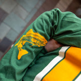 dark green long sleeve tee shirt with single orange stripe in the chest area and one cream stripe above and below. Two Hearted IPA logo in dark green on the left pocket, and image is a detail of orange trout logo on the forearm area of right sleeve