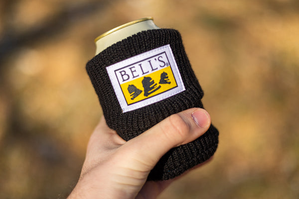 A black cotton beer sleeve with a white yellow, and black Bell's logo sewn onto it.