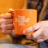Man holding orange Two Hearted branded mug with Two Hearted IPA in white text.