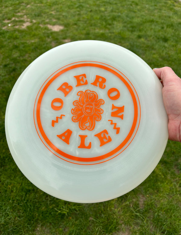 A white glow ultimate disc with small orange Oberon sun surrounded by circular Oberon text in orange. 
