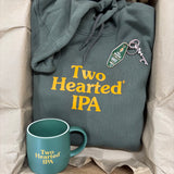 green hoodie with orange 'Two Hearted IPA' text and a matching mug and keychain