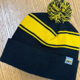Black knit beanie with yellow stripes and a pom with black and yellow.  Also features a Bell's logo tag on the front.