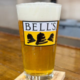 Clear pint glass with yellow and black Bell's logo. Inspired Brewing tagline in black beneath.