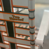 Classic folding lawn chair with aluminum frame with webbing in Two Hearted colors, olive green, orange and white, with white plastic armrests. Featuring Two Hearted Logo in orange font with green outline on back middle right side of chair.