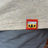 Close-up of a gray heather t-shirt hem with a orange Bells brand patch