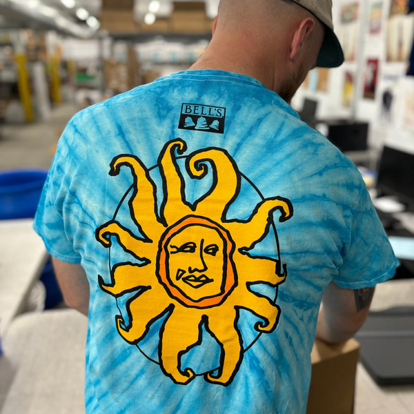 Back of blue tie-dyed short sleeve t-shirt with yellow and orange Oberon sun printed on center back and black Bell's logo at the nape of the neck.