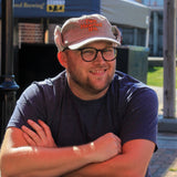 light green corduroy ear flap hat with sherpa liner and Two Hearted text logo embroidered in orange with green outline