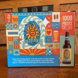 1000 piece puzzle featuring a design that incorporates the Oberon brand logo and beer glasses, hearts, the year 1992, waves, all in the color palette used for Oberon. Orange, gold, blue and sea foam green
