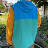 Multicolor windbreaker, teal and blue front of jacket, yellow sleeves, orange drawstring. Blue hood!