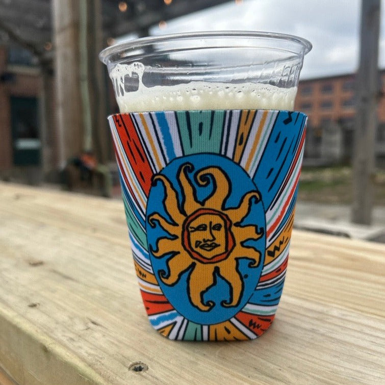 Pint sleeve featuring a starburst of colors, including blue, yellow, sea green, and orange. Features Oberon logo in blue, orange, and yellow.
