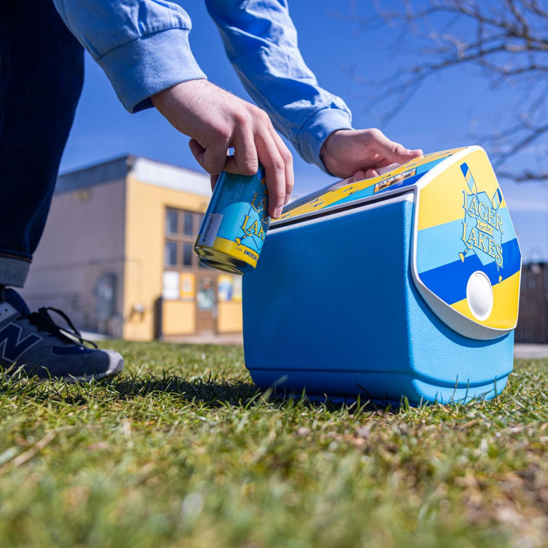 Light blue Igloo cooler with yellow and blue striping on the side panel with Lager for the Lakes Logo. Top of tent style lid has yellow backfground with blue paddles and a Bell's logo.