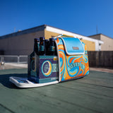 12 pack compacity soft zip up Kanga cooler with sea green Oberon banner printed over marbled orange, gold, blue and sea green. Flaps at the side and tops are solid blue