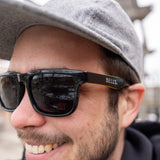 Black malibu style sunglasses with Bells spelled out in white on stem. Inside of stems are yellow