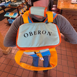colorful color blocked cooler backpack in Oberon colors, blue, teal, gold, and orange with Oberon text printed large on top/opening