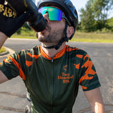 Olive green bike jersey with orange and green camo on the sleeves, with orange collar. The back has large Two Hearted IPA logo on the back, and an orange Bell's logo above it. The back also features Borah logo in orange over middle pocket.