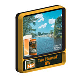 View from left: Two Hearted Ale retro-themed backlit sign with movement effects. Features a scene of the Two Hearted River in Michigan's Upper Peninsula. Features a can of Two Hearted Ale and beer in a pint glass in the lower left corner. At the bottom of the sign, features a Bell's logo with "Since 1985" in far bottom Left. And Two Hearted Ale text in orange with a white border in the bottom right.