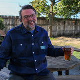 blue plaid flannel shacket with light blue embroidered patch with Oberon Eclipse text logo on pocket.