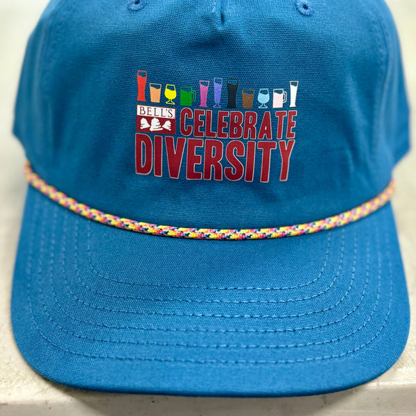 Blue canvas hat with Bell's Celebrate Diversity logo in red.  Above that is a rainbow assortment of different beer style glassware, 11 styles ranging from red to gray. Also featuring rainbow rope between the bill and crown of hat