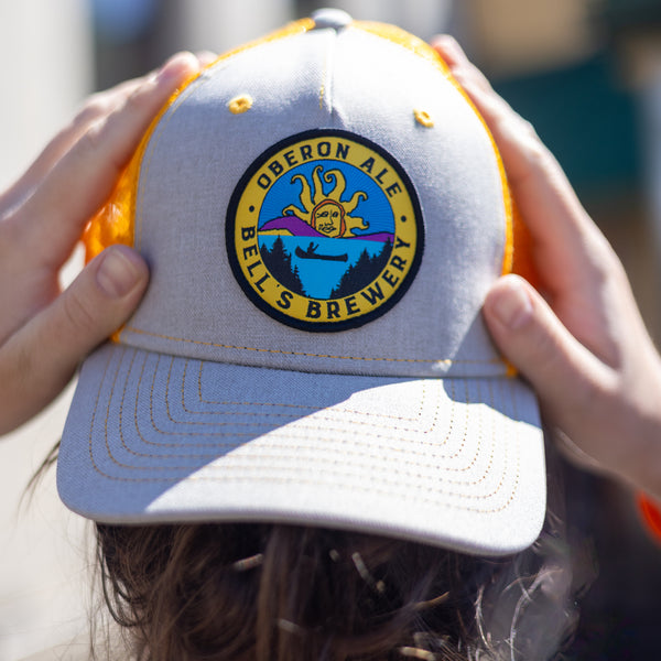 Gray trucker hat with a yellow mesh back featuring an Oberon Ale patch on the front.