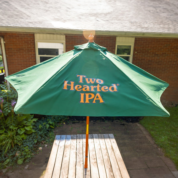 Large green patio umbrella with orange lettered Two Hearted IPA logo printed on side