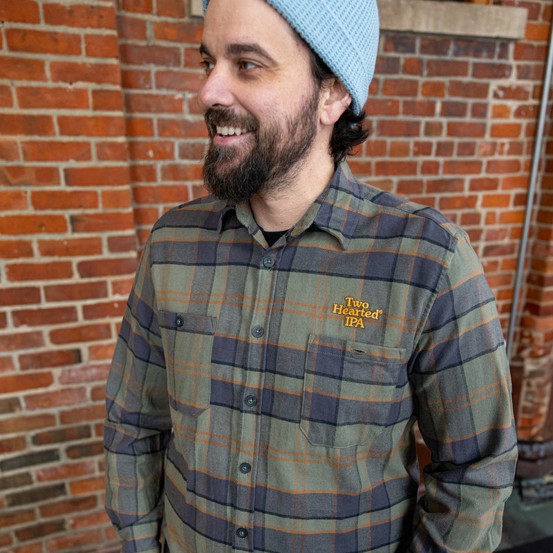 Green with black and orange button up flannel, with two pockets and the "Two Hearted IPA" in orange letters embroidered over the left pocket