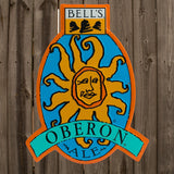 Oberon Ale logo tin sign in shades of blue, orange, and yellow with yellow, balck and white Bell's logo centered on the top. Sign outlined in orange.