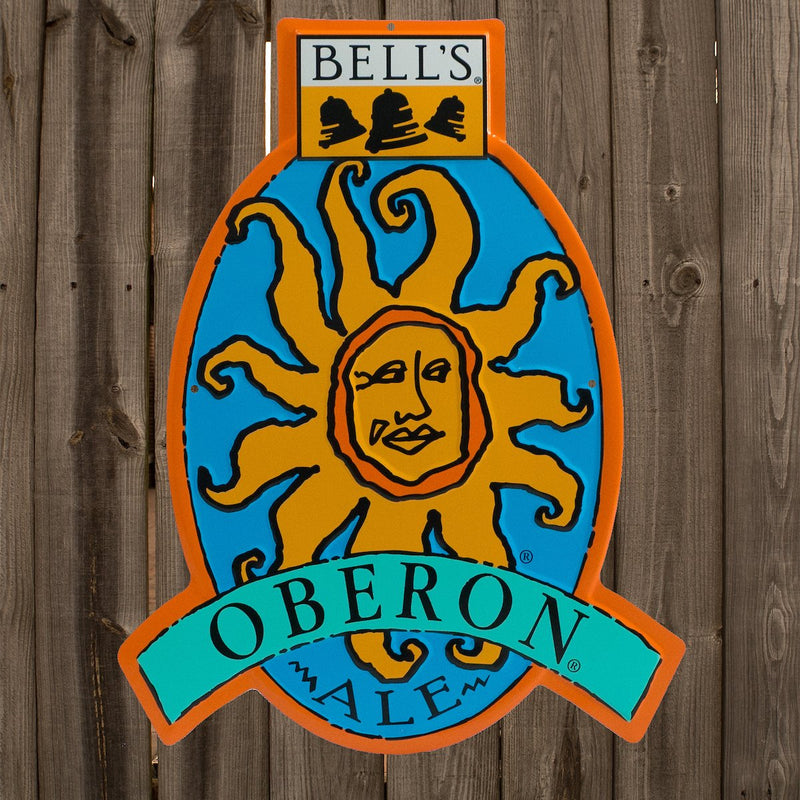 Oberon Ale logo tin sign in shades of blue, orange, and yellow with yellow, balck and white Bell's logo centered on the top. Sign outlined in orange.