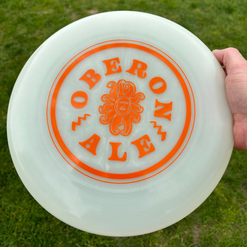 A white glow ultimate disc with small orange Oberon sun surrounded by circular Oberon text in orange. 