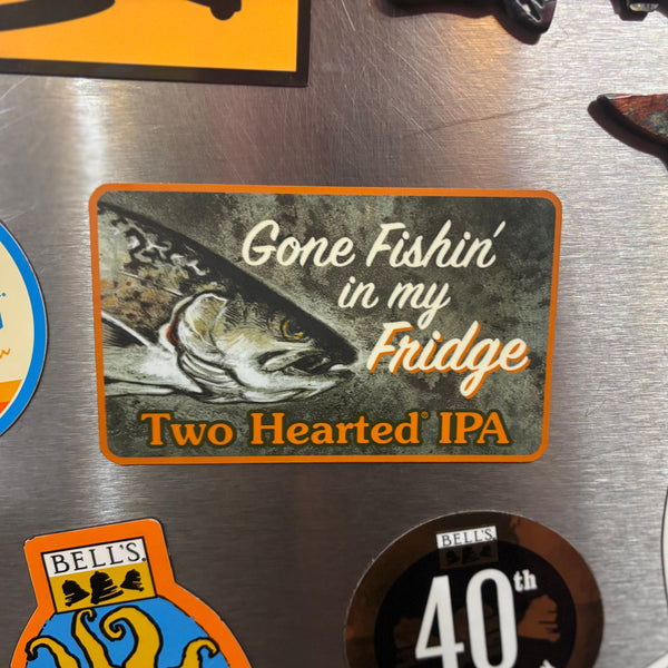 Fridge magnet with 'Gone Fishin' in my Fridge Two Hearted IPA' text and classic fish illustration logo on a metallic surface with other magnets.