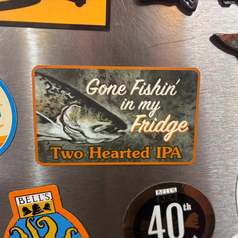 Fridge magnet with 'Gone Fishin' in my Fridge Two Hearted IPA' text and classic fish illustration logo on a metallic surface with other magnets.