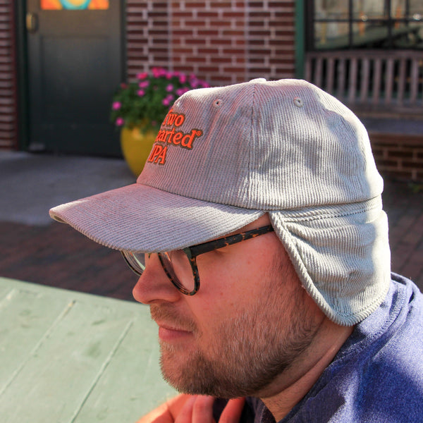 light green corduroy ear flap hat with sherpa liner and Two Hearted text logo embroidered in orange with green outline 
