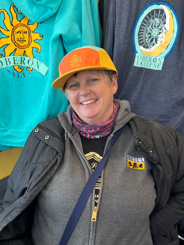 Five panel lightweight polyester cap with different colors for each panel.  Featuring a yellow bill, an orange front with yellow stitched Oberon sun and yellow side panels.  There are also two panels on the top, one being blue and the other teal.