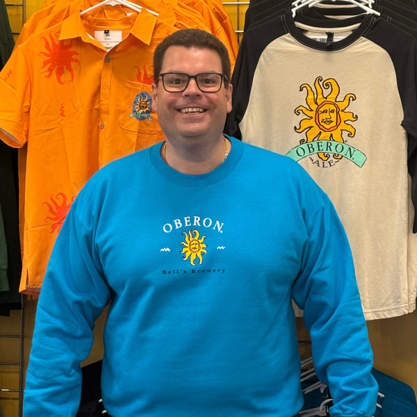 vibrant teal crewneck sweatshirt with Oberon in white lettering above a full color Oberon sun, and Bell's Brewery printed in black below sun.  Graphic is placed front and center on garment