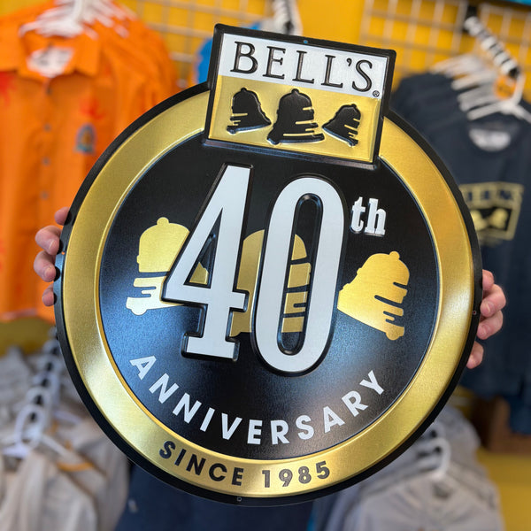 Bell's 40th Anniversary tin sign held in front of a store display with gold and black accent colors. 