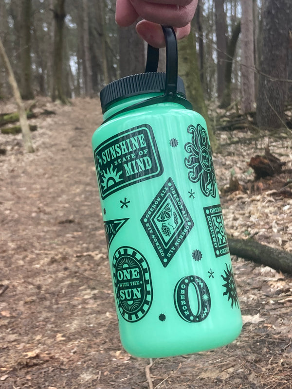 Green glow in the dark 32oz nalgene water bottle with black Oberon logos and sunshine themed images.