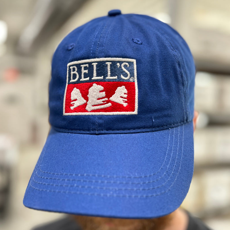 Navy blue dad hat with Bells logo in the center.  The lettering, bells, and the outlining box are white, and the bottom half of the box is red.