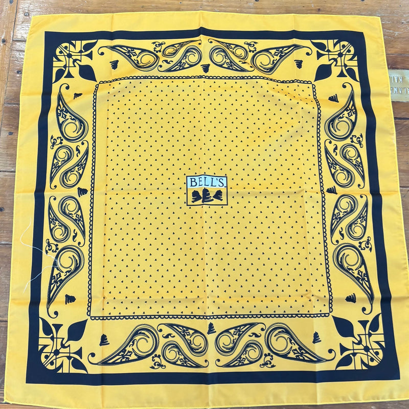 Yellow bandana with paisley border patter and tiny Bells in main body. At the center is a full color Bells logo