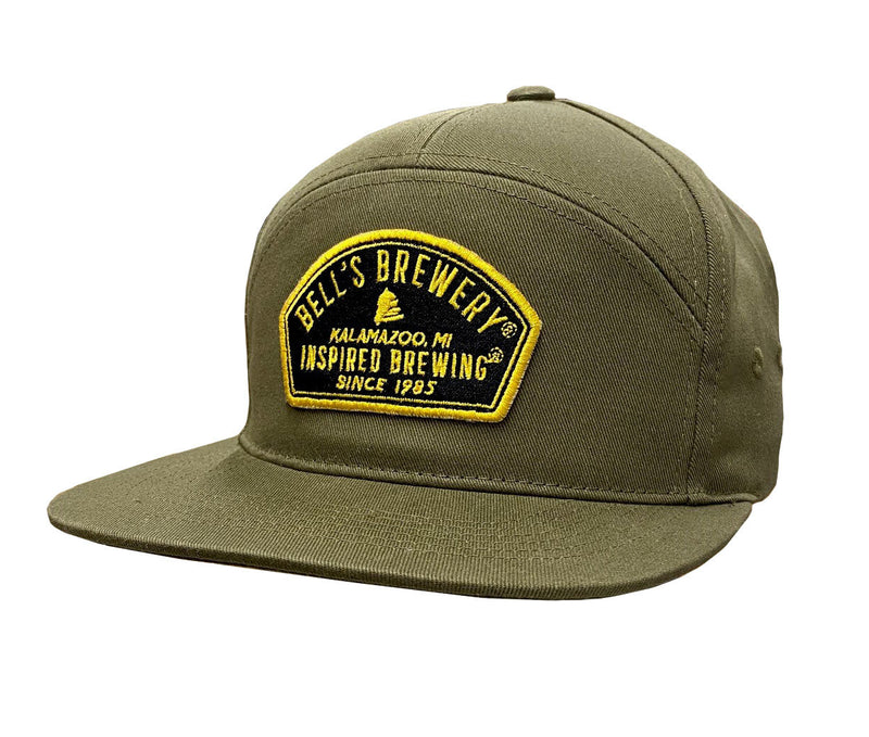 An olive 7-panel hat featuring a black and yellow patch on the front that reads "Bell's Brewery, Kalamazoo, MI, Inspired Brewing Since 1985."