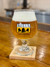 Clear snifter glass with yellow, black and clear Bell's logo. Inspired Brewing tagline in black below.