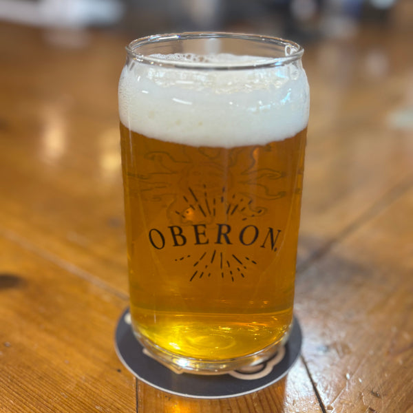 16 ounce can shaped drinking glass with full color Oberon sun on the front, and Oberon printed on the back with sunburst lines surrounding text