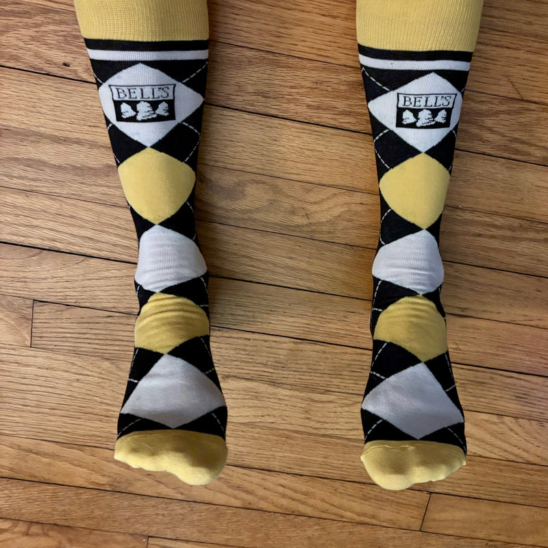 Yellow, black and white argyle socks with yellow top and toes. Bells logo featured in black against white near top of sock. 