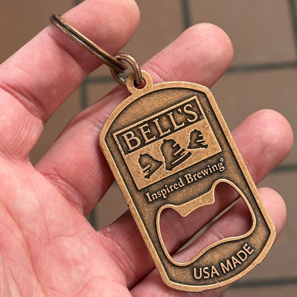 A bottle opener keychain made of a bronze metal with the Bell's logo and the words "Inspired Brewing" and "USA MADE."