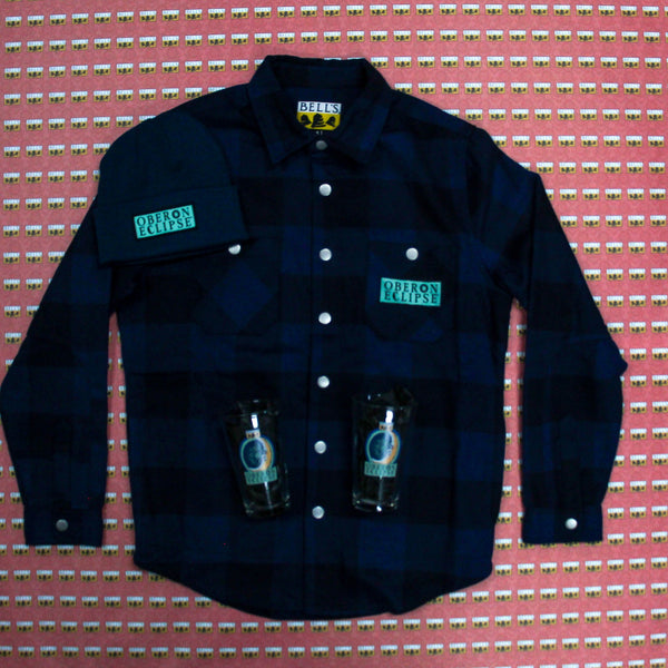 dark blue plaid flannel with Oberon Eclipse text logo patch in light blue, and dark blue beanie with same light blue Eclipse text logo.  Image also features two Eclipse pints featuring full brand art