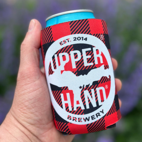 A can sleeve neoprene foam insulator sleeve for 12oz beverage cans. The sleeve is red and black buffalo plaid. The white circular Upper Hand logo is printed on the front. The text 'Drink U.P.' is printed in white across the front.