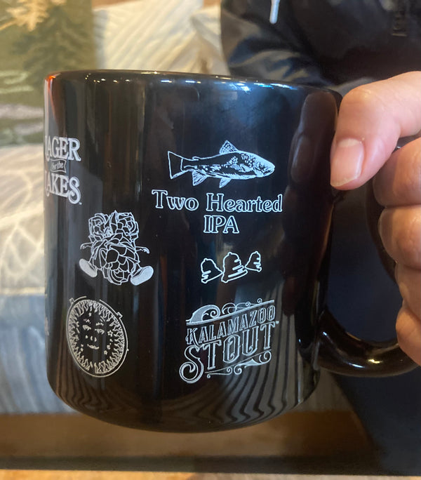 Black coffee mug with multiple Bell’s Beer logos. 