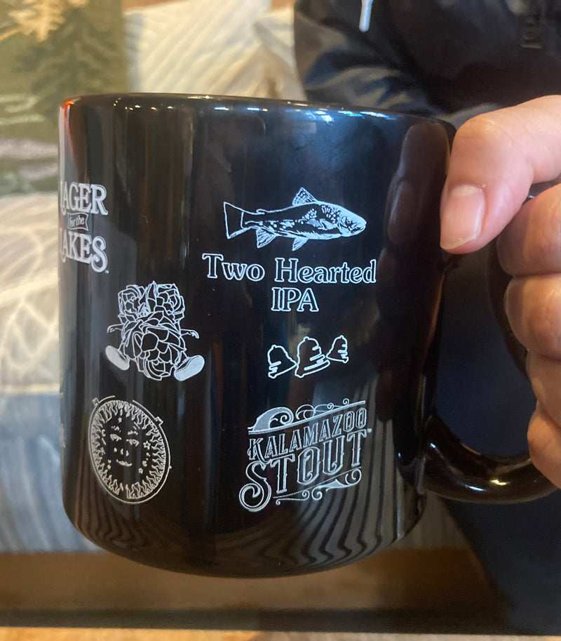 Black coffee mug with multiple Bell’s Beer logos. 