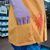 bright orange button up short sleeve shirt with a medium orange Oberon sun silhouette pattern. additional pocket on back lower right.