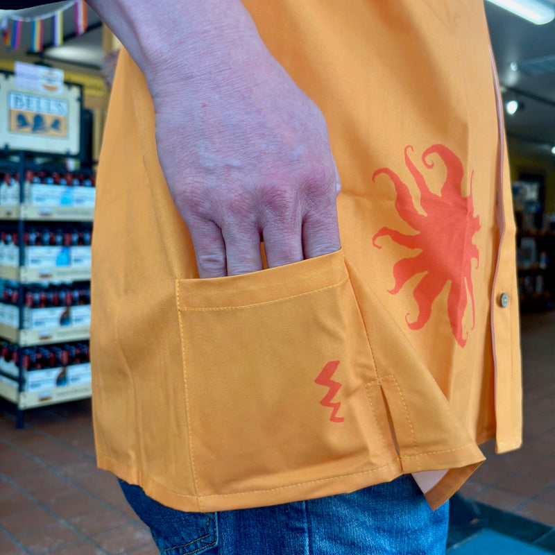 bright orange button up short sleeve shirt with a medium orange Oberon sun silhouette pattern. additional pocket on back lower right.